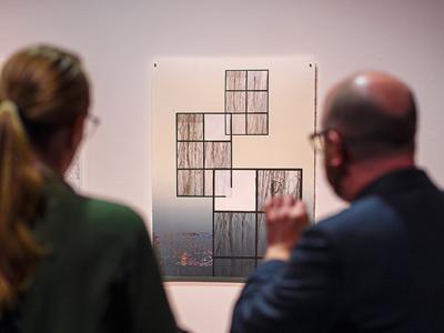 Two people discuss an abstract, printed work of art